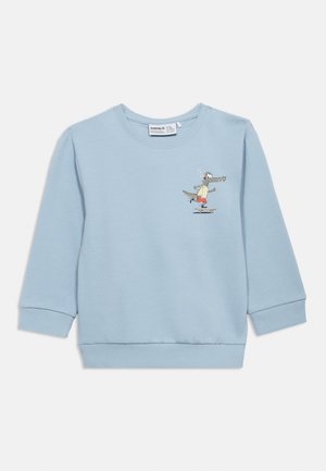 Lys blå langermet barnegenser med en liten tegneseriealligatoren i røde shorts som står på skateboard på venstre bryst.