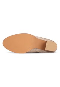 Beige Wildlederschuh mit einer glatten, tanfarbenen Gummisohle. Verfügt über einen niedrigen Blockabsatz und einen strukturierten Grip auf der Sohle für besseren Halt.