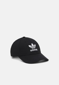 Svart baseballkeps i tyg med en styv skärm. Har en vit broderad Adidas-logotyp med trebladig design på framsidan.
