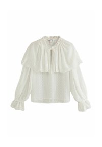 Blouse blanche à manches longues en tissu texturé, col à volants, superposition type cape et poignets élastiqués avec détail en dentelle.