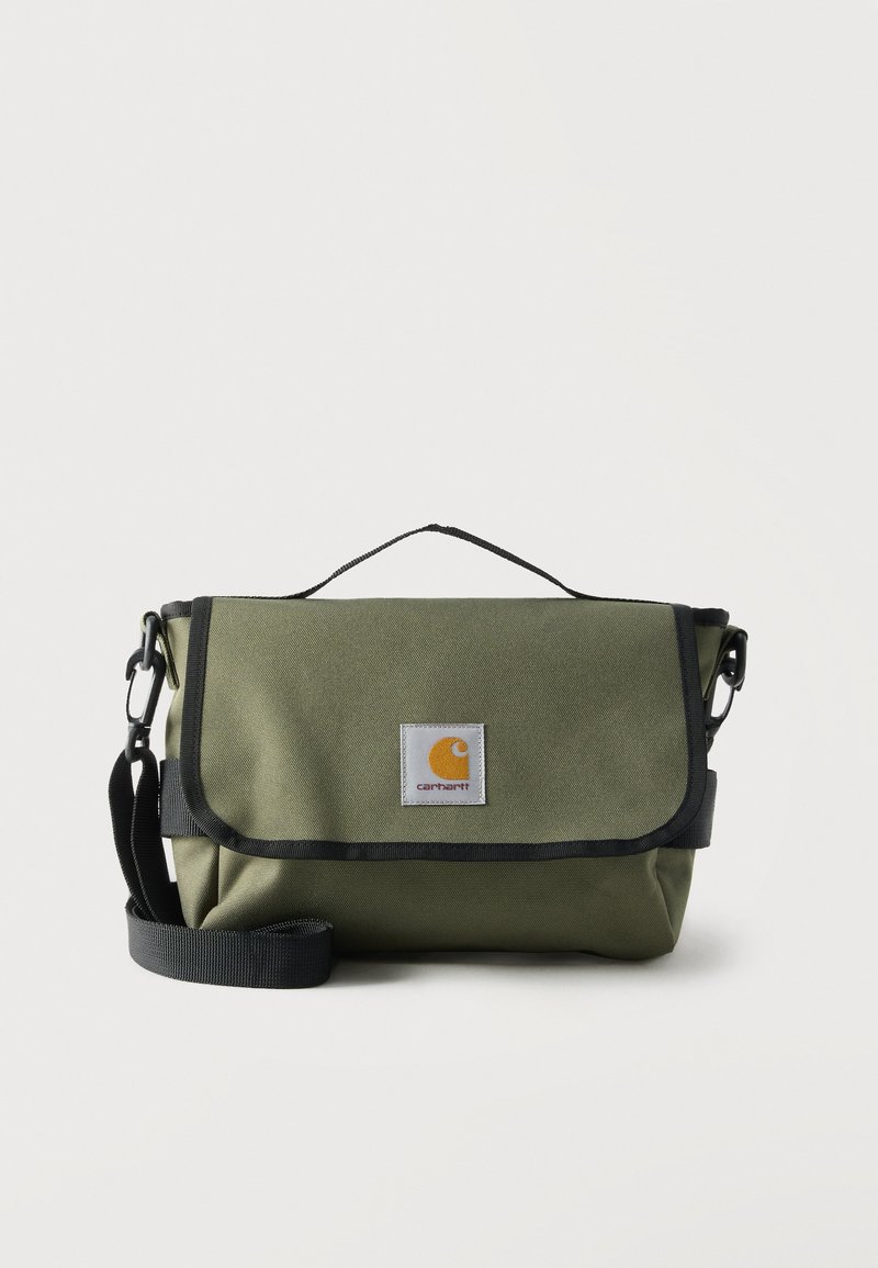 Olijfgroene Carhartt schoudertas met zwarte biezen, verstelbare schouderband, bovenste handvat en vooraan een logo op een witte achtergrond.