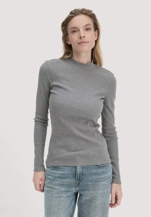 Graues geripptes Langarmoberteil mit hohem Kragen, kombiniert mit hellblauen Jeans. Der Stoff hat eine weiche Textur und eine figurbetonte Passform.