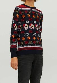 Granatowy sweter dzianinowy z festiwalowymi wzorami, w tym czapki Mikołaja, prezenty i serca, z czerwonymi i żółtymi akcentami oraz okrągłym dekoltem.