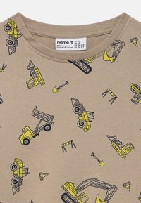 Μπεζ παιδικό πουκάμισο με μοτίβα από κίτρινα κατασκευαστικά οχήματα, φτυάρια, κώνους κυκλοφορίας, φράγματα και εξοπλισμό.