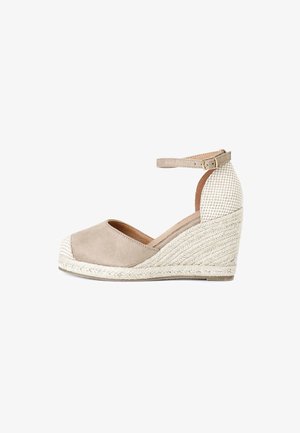 Scarpa con tacco a cuneo in suede beige con cinturino alla caviglia e tacco intrecciato texturizzato. Presenta una punta aperta e un design morbido e curvato.