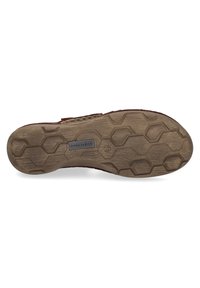 Brown rubber shoe sole with a hexagonal pattern. Notable details include a textured surface and an embedded logo plate.