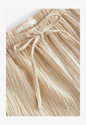 Beige tekstureeritud kangast lühikesed püksid, millel on koondatud elastne vöökoht, esiküljel on lips ja sildil on kiri "next".