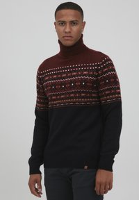 Strickpullover mit Stehkragen in einem burgunder- und dunkelblauen Farbschema, mit geometrischen Mustern im oberen Bereich und gerippten Bündchen.