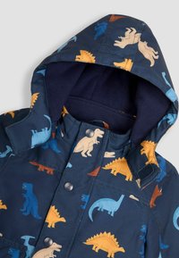 Giacca blu con motivo di dinosauri, dotata di un morbido cappuccio, caratterizzata da varie silhouette di dinosauri in arancione, giallo e teal. Chiusure a bottone e Velcro.