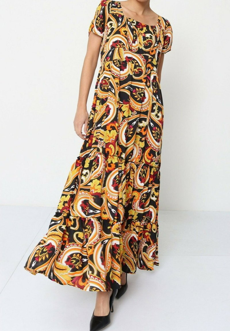 Robe maxi en tissu noir avec un motif paisley vibrant rouge, jaune et vert. Elle présente des manches courtes et un design en couches fluide.