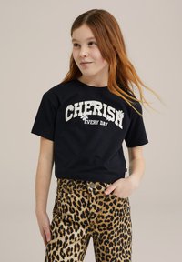Svart kortärmad t-shirt med "CHERISH EVERY DAY" tryckt i vitt, tillsammans med byxor i leopardmönster med hög midja och knäppning.