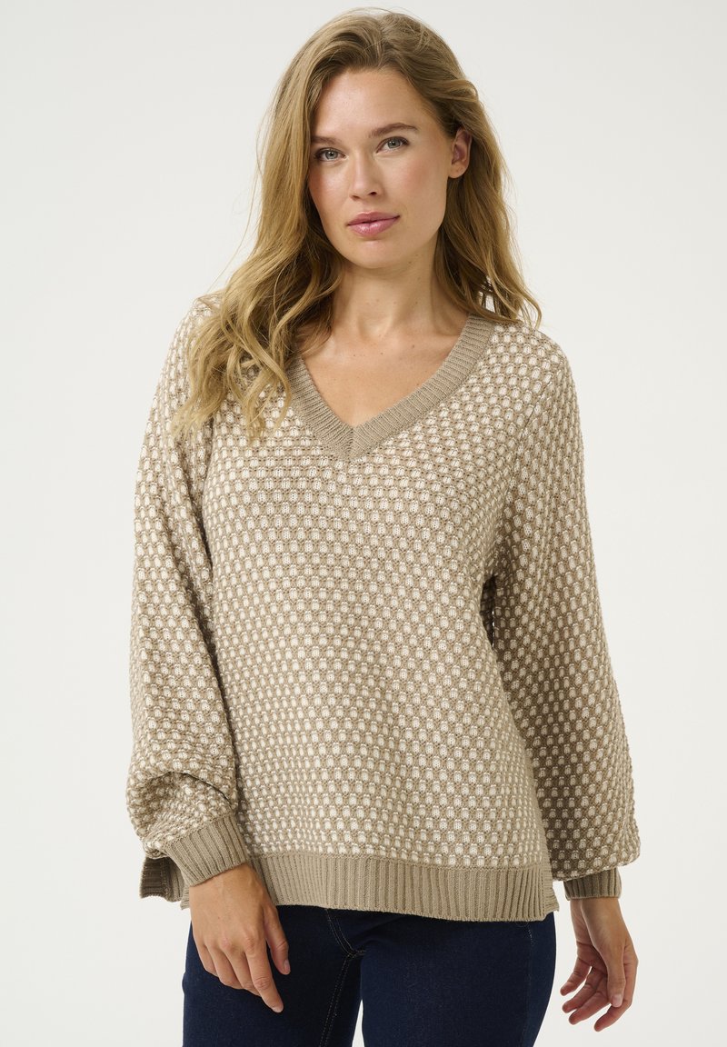 Beige mönstrad tröja med v-hals, texturerad väv och ribbade muddar och fåll. Oversized passform med en bekväm fall.