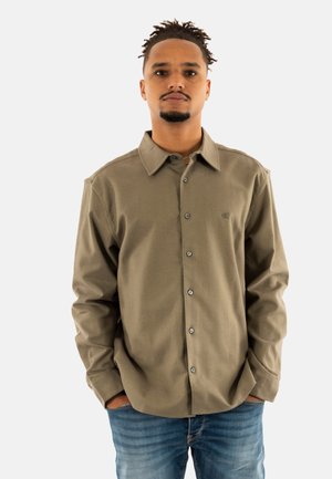 Camisa de botones de color verde oliva hecha de un material suave, con un cuello clásico, botones plateados y un logo sutil en el pecho.
