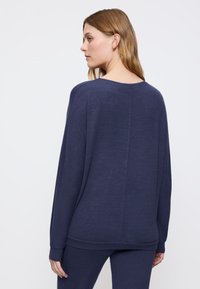 Maglione oversized blu navy con maniche lunghe, scollatura rotonda e tessuto testurizzato. Presenta un taglio dritto e dettagli di cucitura sottili sul retro.