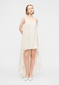 Δαντελένιο φόρεμα slip σε εκρού χρώμα με V-λαιμόκοψη και ασύμμετρη γραμμή στο τελείωμα, με υφή στο ύφασμα και λεπτές τιράντες στους ώμους.