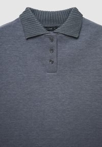 Polo shirt navy con colletto a coste, quattro bottoni neri e una texture morbida. Il tessuto ha una leggera lucentezza e una finitura liscia.