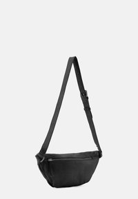 Borsa a tracolla in pelle nera con forma curva, tracolla regolabile e tasca con zip frontale; texture liscia e design minimalista.