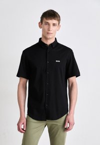 Camicia nera a maniche corte con bottoni, dotata di colletto classico e logo "BOSS" ricamato sul petto, realizzata in un tessuto liscio.