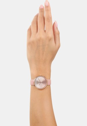 Rosa Silikonarmbanduhr mit einem metallischen roségoldenen Gehäuse und einem hellrosa Zifferblatt. Sie verfügt über einfache Stundenmarkierungen und ein minimalistisches Design.