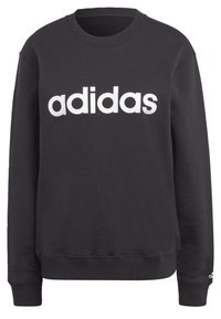 Svart bomullströja med rund hals, ribbade muddar och en stor vit "adidas"-logotyp på framsidan. Mjuk textur, avslappnad design.