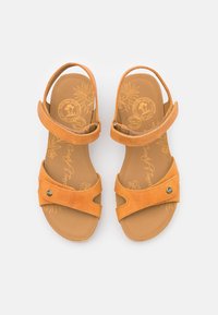 Paire de sandales ouvertes en cuir tan avec brides ajustables à la cheville et aux orteils, design floral sur la semelle intérieure, et bouton métallique de marque sur les brides des orteils.