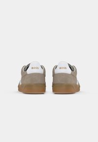 Herresneakers i beige semsket skinn med hvite detaljer og såle av gummigummi. Har logo på helen og rundt tådesign.