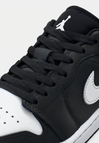 Black leather sneaker with white accents, featuring a high-top design, flat black laces, and a prominent Jumpman logo on the tongue.