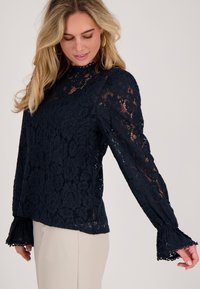 Navyblauwe kanten top met lange mouwen, bloemmotief, golvende halslijn en manchetten, met een losse pasvorm en een gestructureerde afwerking.