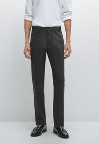 Pantaloni grigi sartoriali realizzati in tessuto liscio, dal taglio dritto, con chiusura a bottone e tasche frontali. Abbinati a mocassini neri.