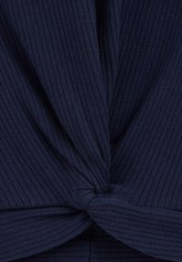 Top bleumarin cu nervuri, având un detaliu de nod răsucit la talie, țesătură texturată și un model vertical de nervuri pe întreaga suprafață.