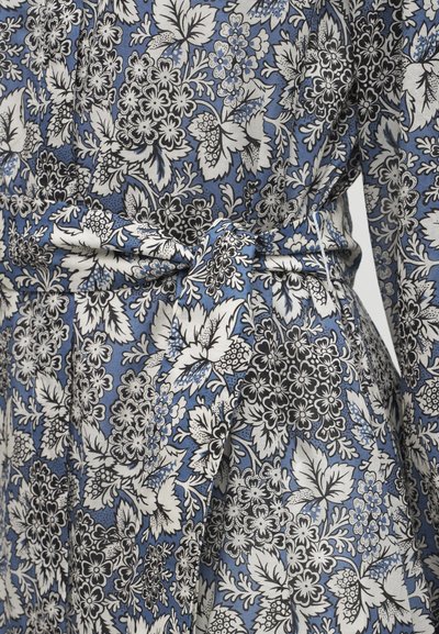Μπλε ύφασμα με πυκνά μαύρα και λευκά λουλουδάτα και φυλλώδη σχέδια, με δεμένη ζώνη στη μέση.