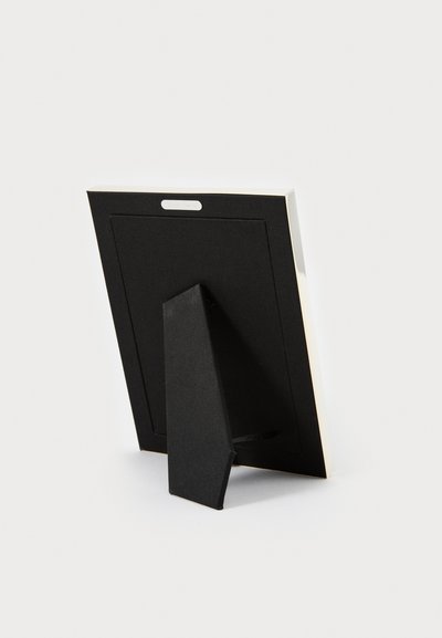 Czarne ramki na zdjęcia z teksturowanym tyłem, stojakiem ustawionym pionowo oraz białą krawędzią. Posiada małą metalową zawieszkę u góry do mocowania na ścianę.