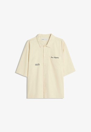 Lyhythihainen, napitettava paita vaaleanbeigessä kankaassa, jossa on tekstuuri. Sisältää rintataskun, jossa on brodeerattuna "Uudet luvut" ja "NRL".