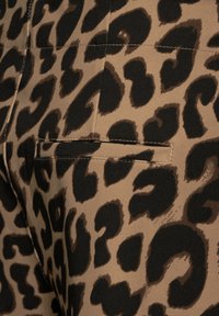 Leopardenmusterstoff in Brauntönen und Schwarz, mit einem eleganten Design, subtilen Taschenakzenten und glatter Textur.
