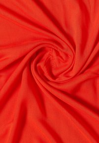 Tissu rouge torsadé en une spirale centrale, montrant une texture lisse et des plis rayonnants vers l'extérieur.