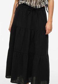 Juodas sluoksniuotas sijonas, pagamintas iš lengvos medžiagos. Yra elastinga juosta su raišteliu ir plazdančios siluetas.