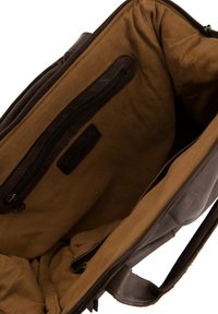 Dark leather bag interior featuring a smooth brown fabric lining, a zippered pocket, and a VENEZIA logo patch. Side fabric texture is plain.