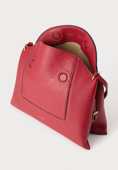 Sac à main en cuir rouge texturé avec fermeture magnétique, ferrures dorées et ouverture supérieure montrant la doublure intérieure beige.