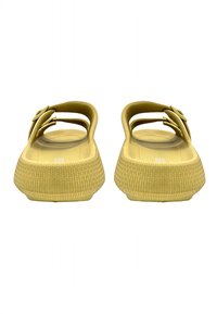 Gele rubberen sandalen met een platte zool, open hiel en twee verstelbare banden. Textuur in de voetbed voor grip en comfort.
