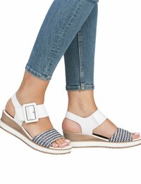 Sandales compensées blanches avec une sangle à motif zigzag bleu marine et blanc, boucle réglable et semelle texturée. Design décontracté adapté pour l'été.
