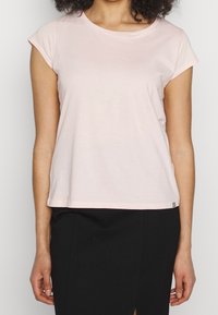 T-shirt in cotone rosa chiaro con maniche corte, scollatura rotonda e vestibilità morbida. Presenta un piccolo accento a righe nere all'orlo.