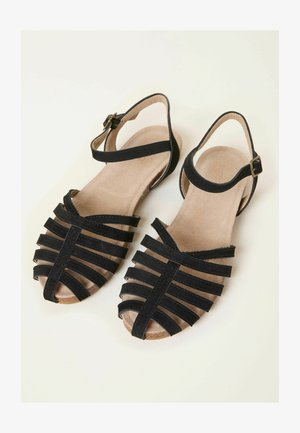 Sandale negre cu barete, cu partea superioară moale și texturată, design cu vârf deschis, curea reglabilă la gleznă și talpă plată de culoare cărămizie.