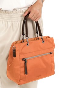 Orangefarbene Stofftragetasche mit braunen Ledergriffen, einer vorderen Reißverschlusstasche und silbernen Hardware-Akzenten. Glatte Textur, rechteckige Form.