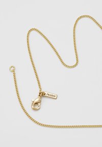 Collana in oro con un gancio e un'etichetta con la scritta "PILGRIM". La catena ha una texture liscia e lucida e un design a maglie classico.