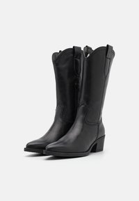 Botas de vaquero de cuero negro con puntera puntiaguda, bordes ondulados y tacón bajo. Cuentan con un cierre lateral y un acabado suave.