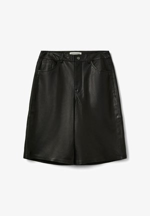 Musta nahast seelik, millel on sile pind, kõrge vöökoht, ees taskud ja sirge lõige. Omaduseks on ees olev nööbikinnitus ja õmbluste detailid.