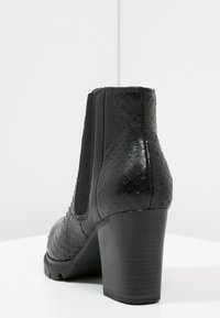 Sort ankelstøvle med hæl, der har et struktureret slangeskindsdesign, elastiske sidepaneler og en kraftig hæl. Glat overflade og elegante linjer.