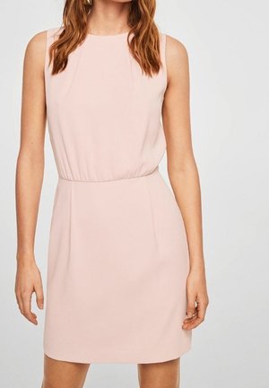 Bez rękawów, jasnoróżowa sukienka do kolan z dopasowaną talią i okrągłym dekoltem, noszona przez kobietę z falującymi brązowymi włosami.