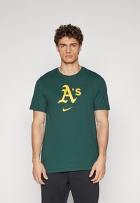 Zelené bavlnené tričko s veľkým žltým logom "A's" a emblémom Nike. Krátke rukávy a okrúhly výstrih s voľným strihom.