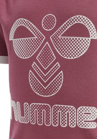 Vinröd T-shirt med en vit prickmönstrad grafik av abstrakta former och ordet "hummel" i en fet prickad stil. Mjuk tygtextur.